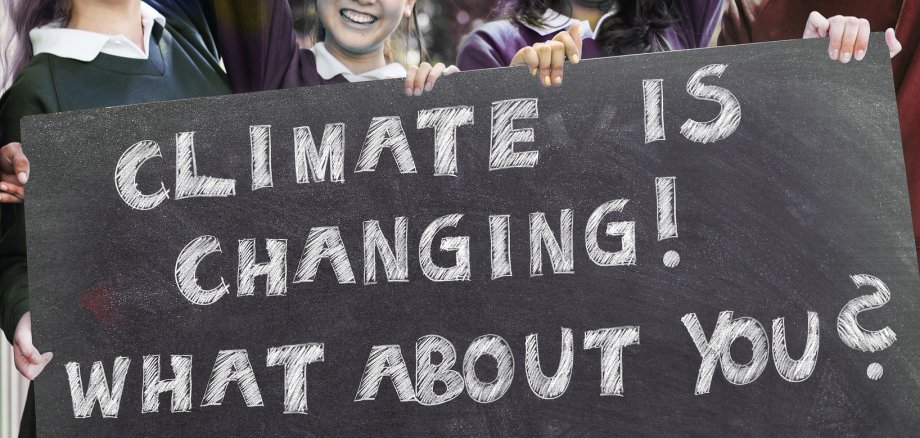 An dieser Stelle ist ein Bild von einer Protestantin mit einem Schild, worauf "Climate is changing! What about you?"